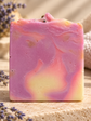 A rectangular handmade soap bar with pink, purple, and pale yellow marbled swirls,